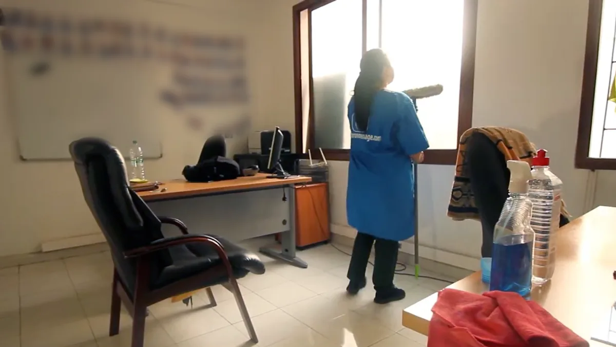 Une intervenante Chronomenage nettoie les vitres d'un bureau