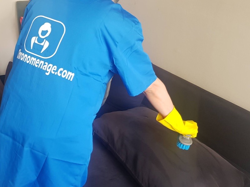 Une intervenante Chronomenage brosse un coussin de canapé avant le nettoyage à sec