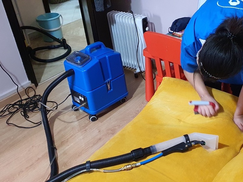 Machine d'injection-extraction et coussin de canapé jaune en cours de nettoyage